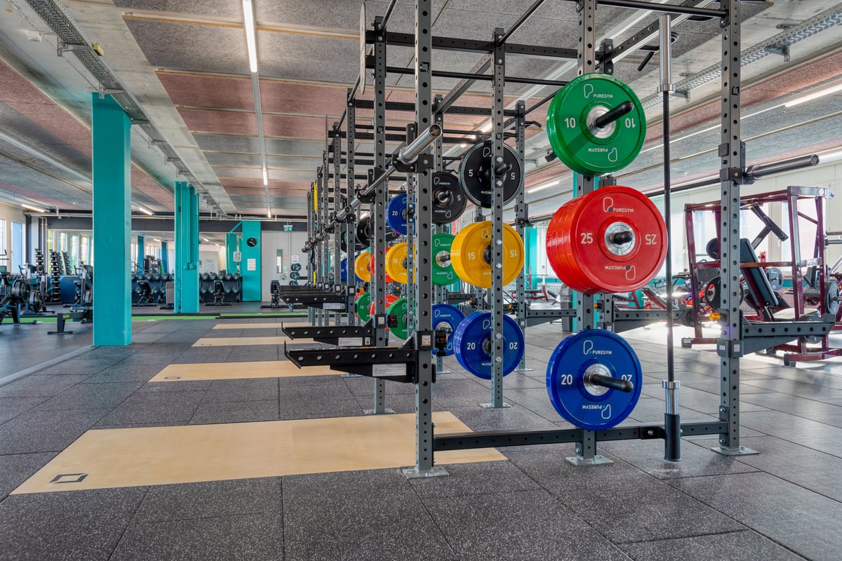 PureGym Wetzikon: Fitnessstudio mit Hockstützen, Hantelscheiben in verschiedenen Farben und gummiertem Boden.
