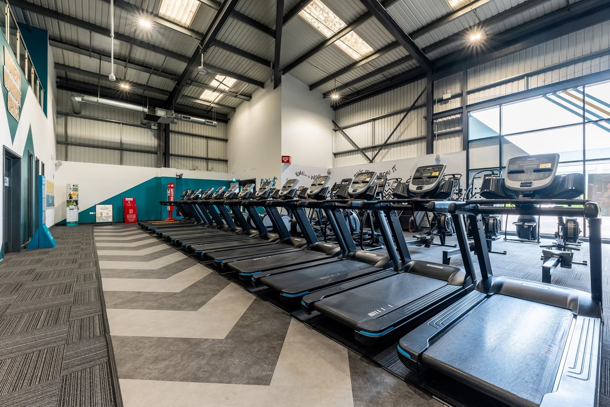 PureGym Leamington Spa: Rows of treadmills inside a well-lit gymnasium space with high ceilings.