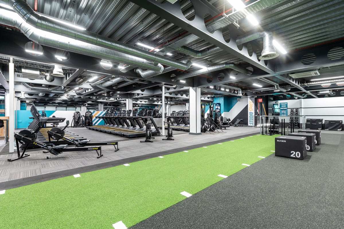 PureGym Manchester Spinningfields: Weight benches, squat racks, turf area, and resistance machines.