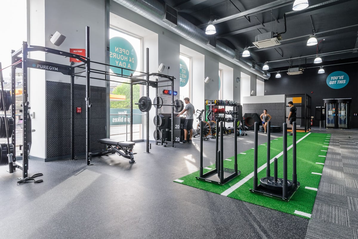 PureGym Dundee: Free weights, squat racks, turf training area, and rubberized flooring in a gym setting.
