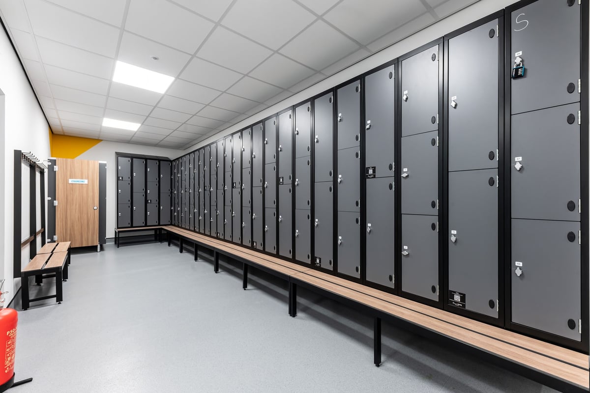 PureGym Ipswich Ravenswood: Rows of lockers, benches, and changing area with yellow accent wall.