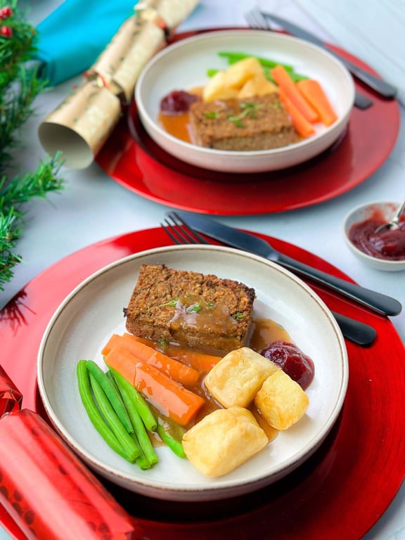 Vegan roast dinner with green beans, carrots, roast potatoes, gravy, and cranberry sauce o