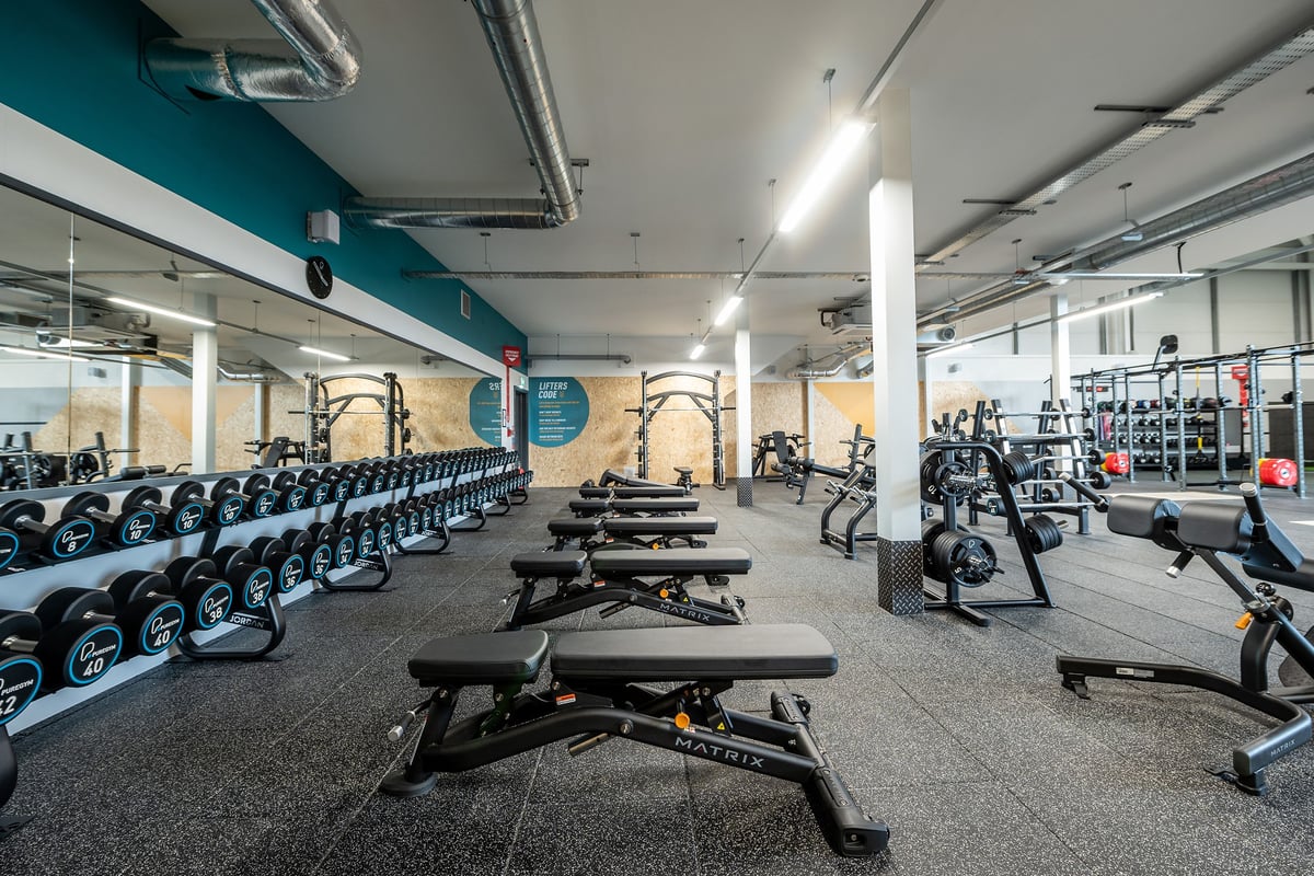 PureGym Trowbridge: Rows of weight benches, dumbbell racks, and exercise machines on rubberized gym flooring.