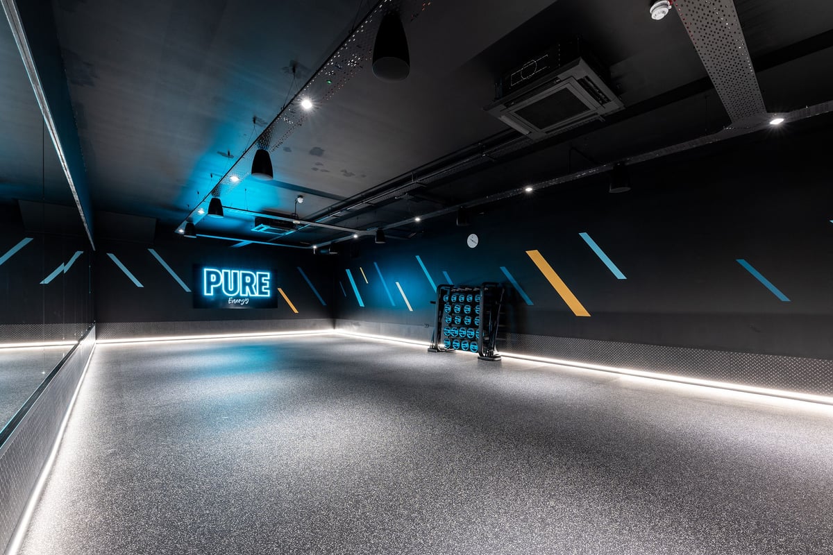 PureGym Consett: Treadmills, turf area, functional training rig, neon blue and orange lighting.