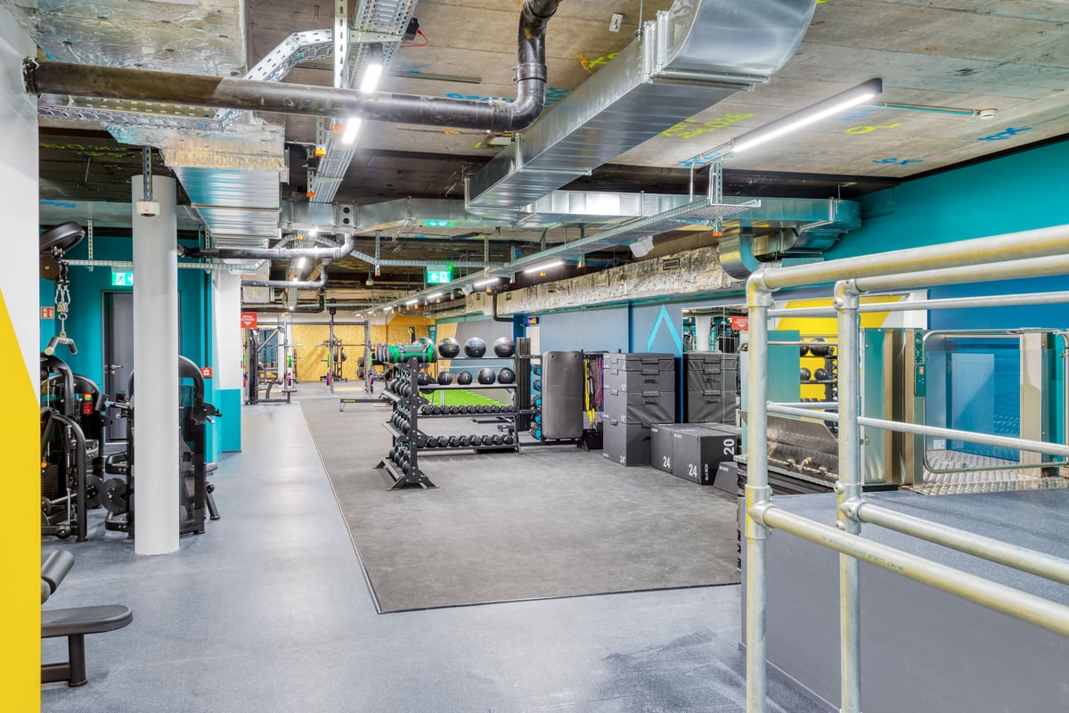 Une vue grand angle d'une gym montrant des râteliers d'haltères, des ballons lestés, des plyo boxes, des bandes de résistance et des machines de musculation