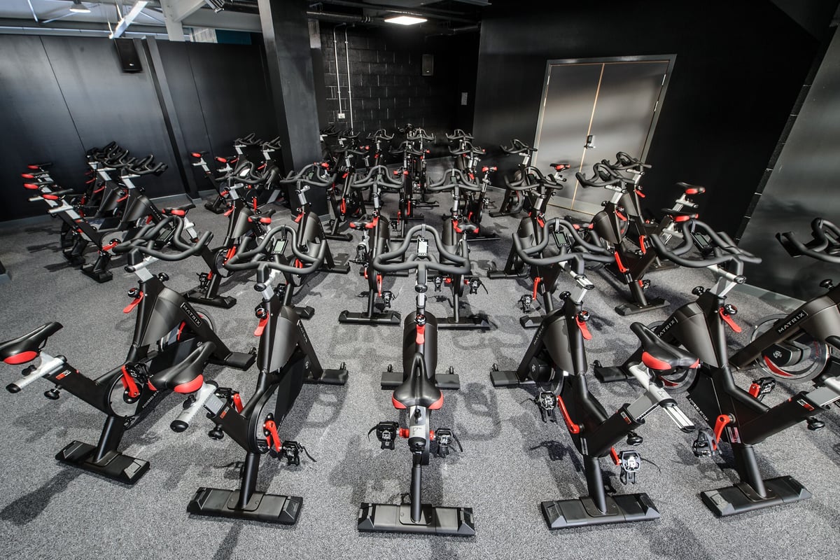 PureGym Leeds Kirkstall Bridge: Rows of stationary bikes neatly lined up in a dimly lit fitness studio.