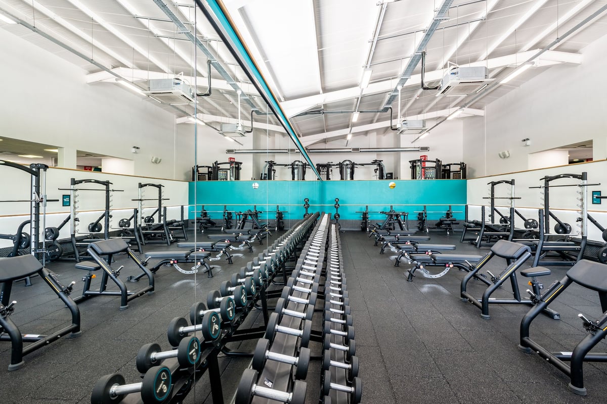 PureGym Northwich: Rows of treadmills, bikes, and weight machines with turquoise accents lining a bright gym interior.