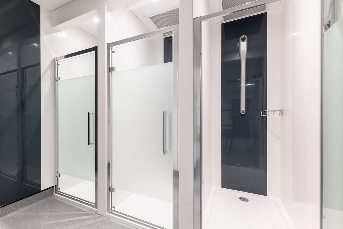 PureGym Dagenham: Shower cubicles with glass doors, tiled walls, and accessible shower handles.