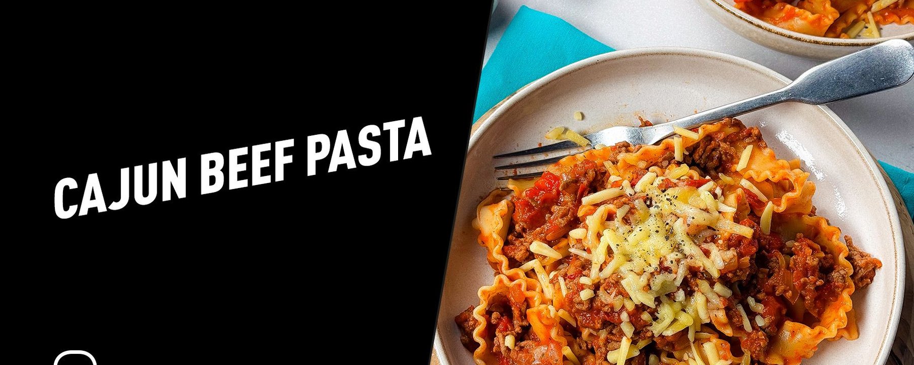Two plates of Cajun beef pasta topped with grated cheese and black pepper with forks