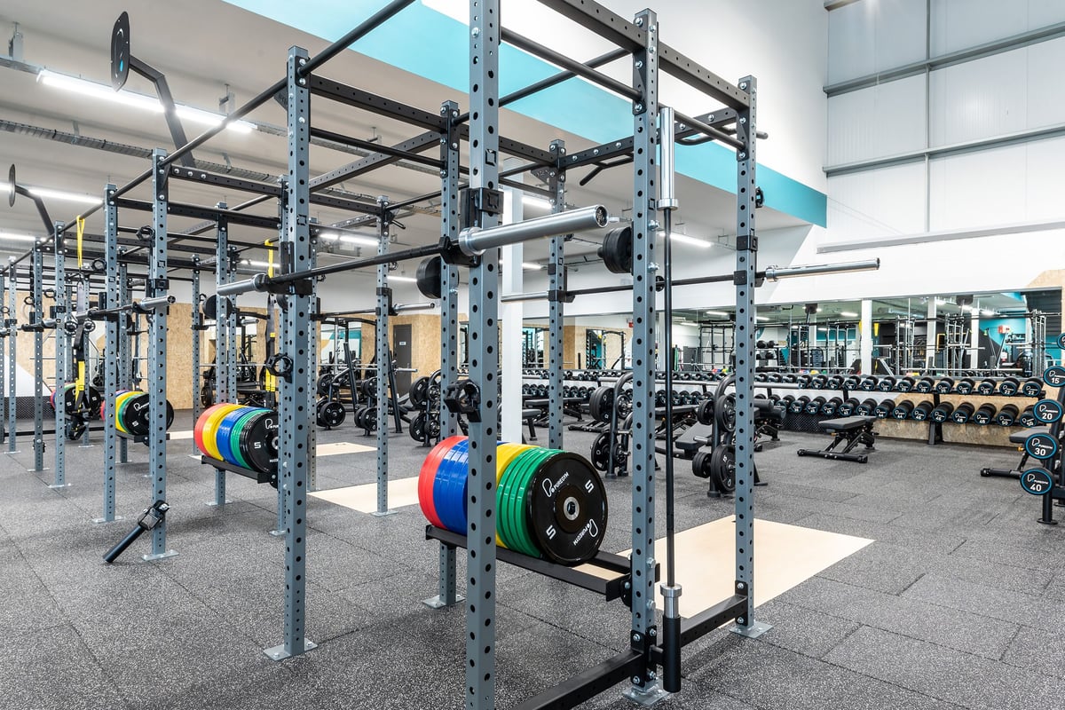 PureGym Nottingham West Bridgford: Power racks, weight plates, dumbbells, benches, and rubberized flooring in a gym.