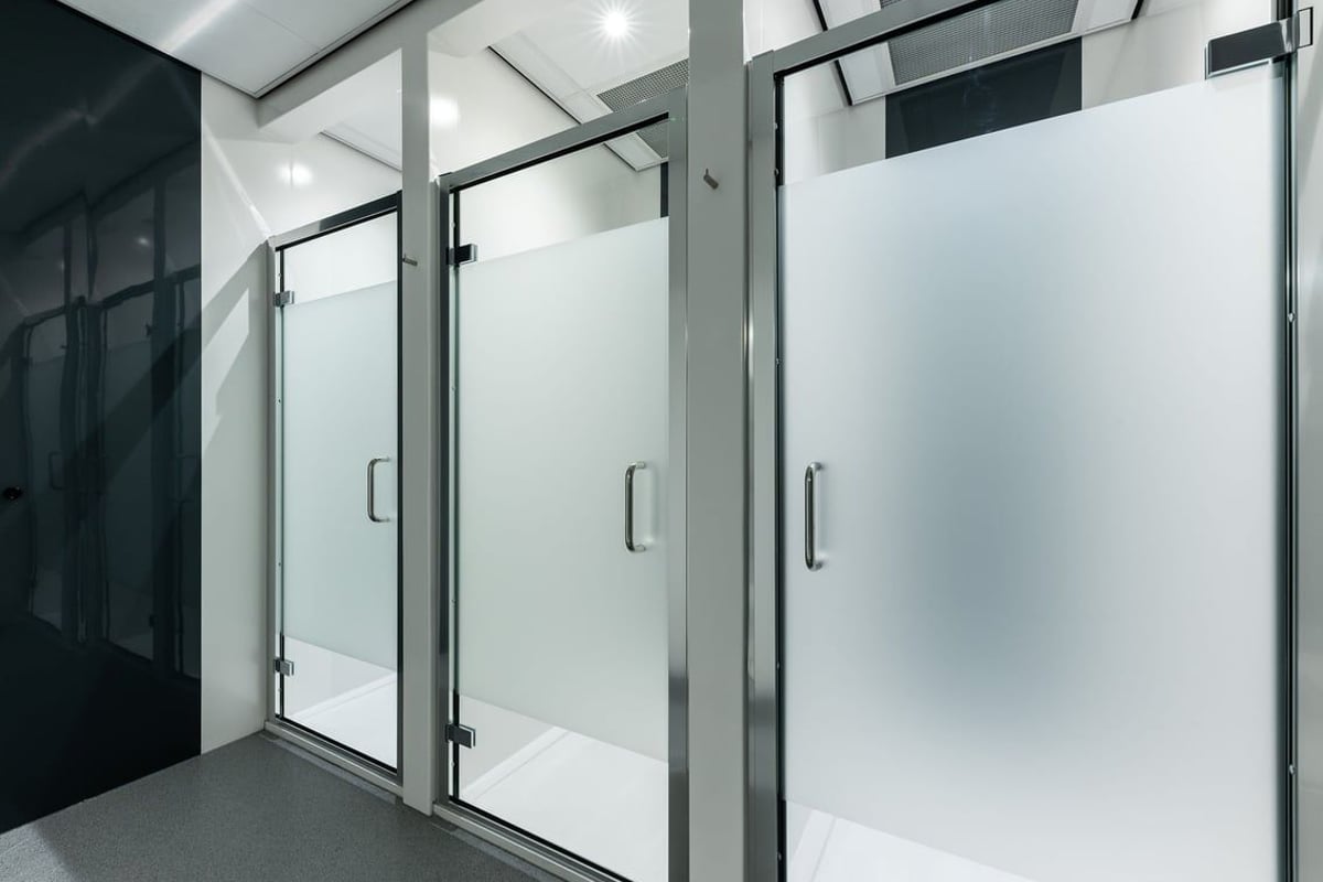 PureGym Great Yarmouth: Shower stalls with glass doors and handles in a tiled bathroom area.