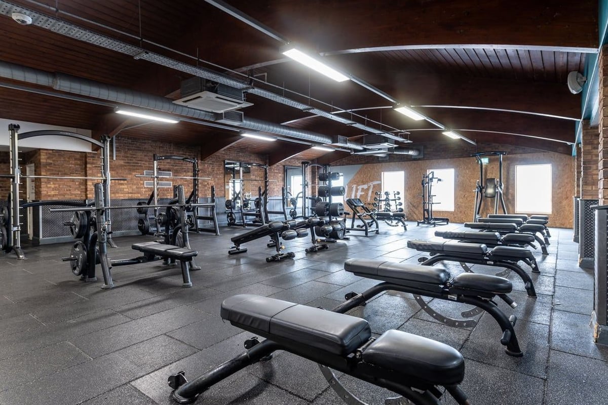 PureGym Northolt: Weight benches, resistance machines, free weights, and exposed brick walls in a gym setting.
