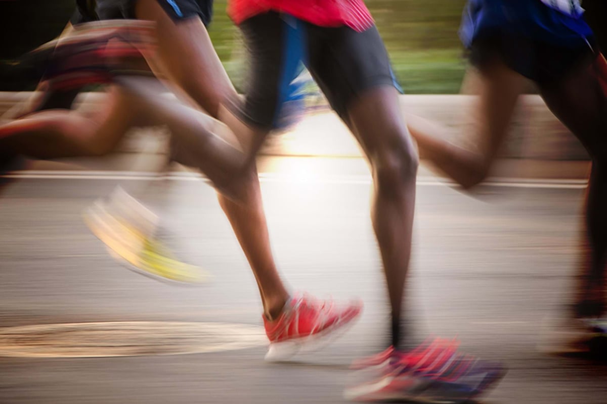 blurred legs of runners in motion on a road during a race