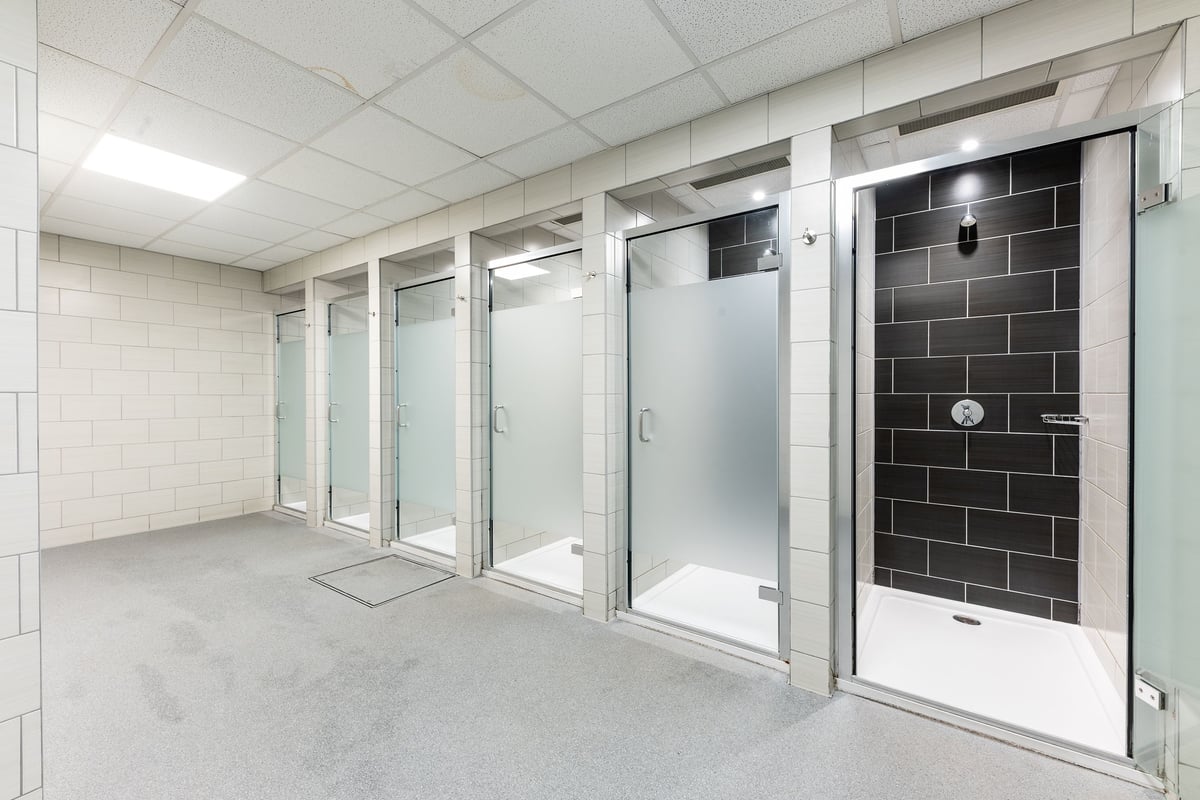 PureGym Purley: Shower and changing cubicles with tiled walls, glass doors and concrete floors.