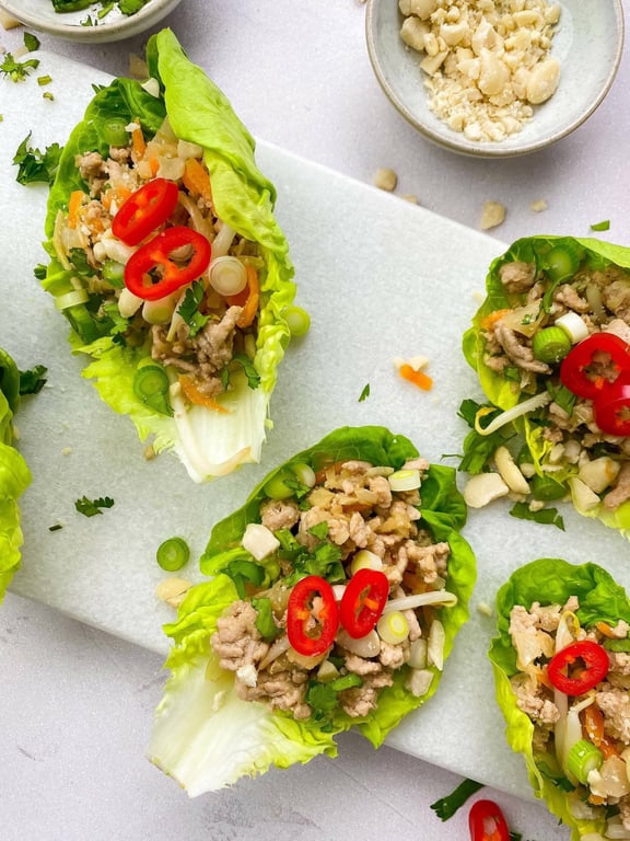 Lettuce wraps filled with minced meat, sliced red chili, spring onions, and herbs