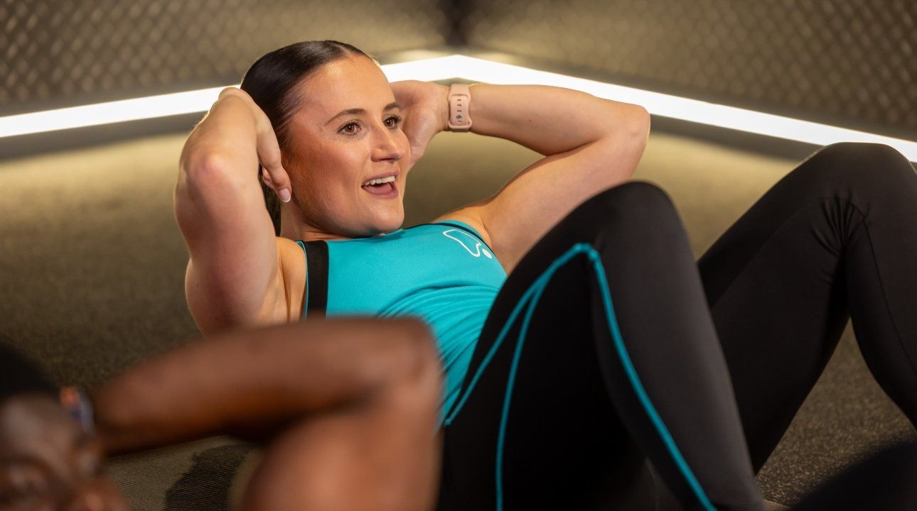 Female fitness coach performing sit up class