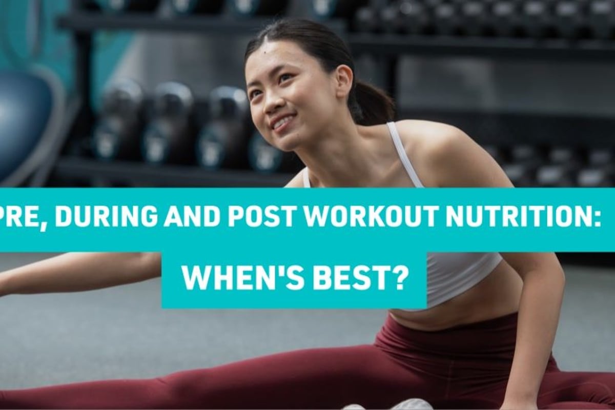 Woman in sportswear stretching on gym floor with dumbbells in background