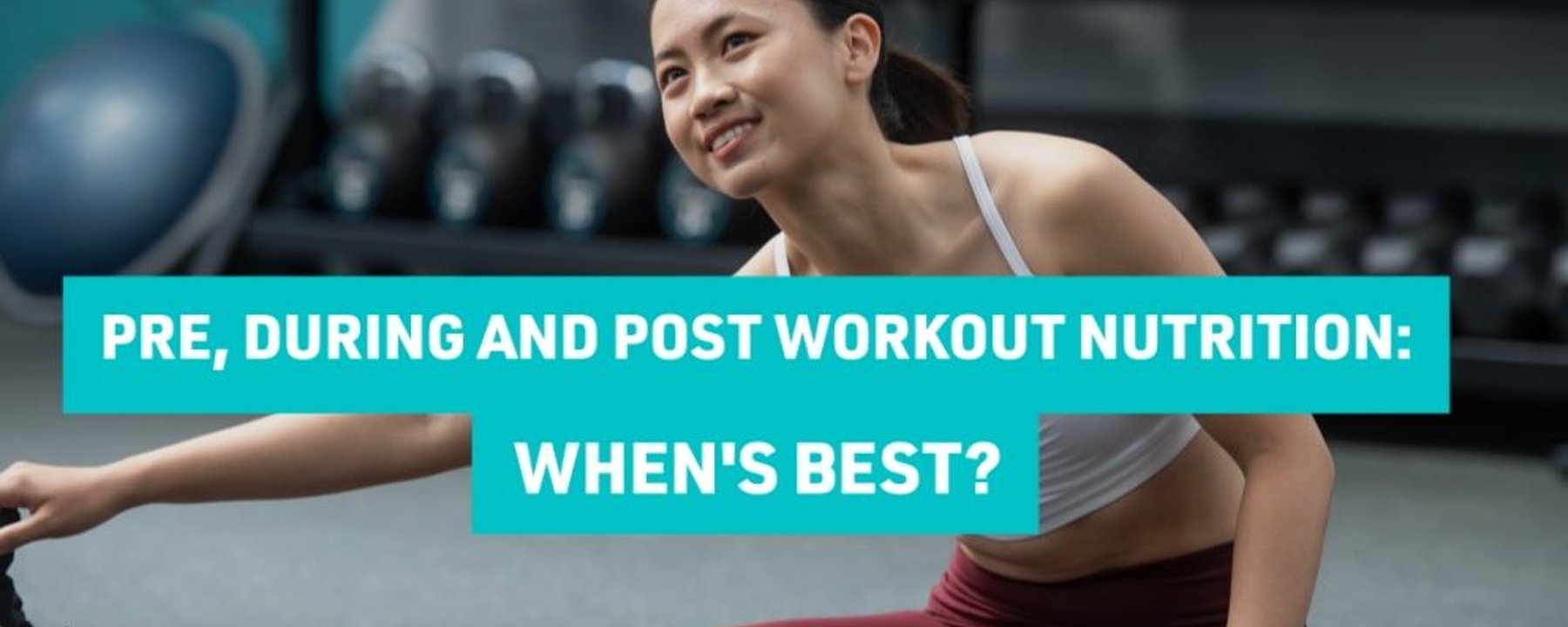 Woman in sportswear stretching on gym floor with dumbbells in background