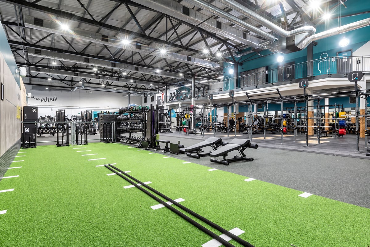 PureGym York: Bright gym interior with weightlifting platforms, squat racks, functional training turf, and mirrored walls.