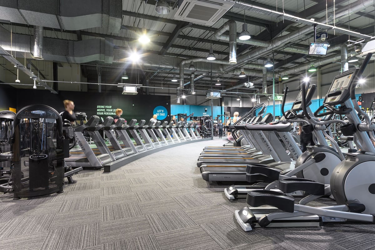 PureGym Bromborough: Rows of treadmills, ellipticals, exercise bikes, and other cardio equipment in a large gym space.