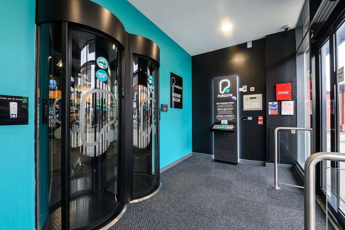PureGym London Acton: Tanning beds and foyer area with kiosks and signage.