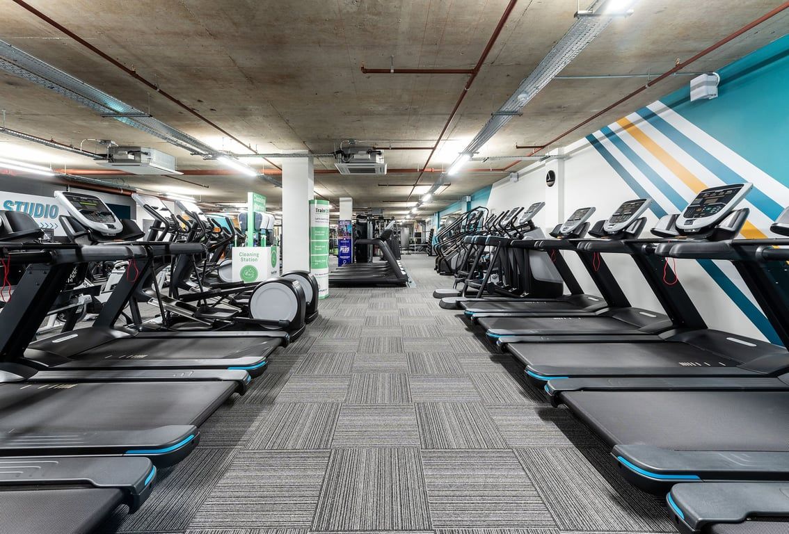PureGym London Angel: Rows of treadmills, ellipticals and other cardio machines in a dimly lit gym.