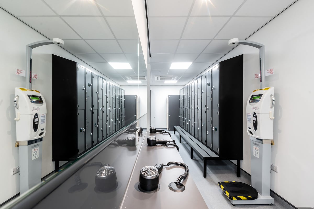 PureGym Newbury: Rows of lockers, charging stations, and isolated flooring in a brightly-lit space.
