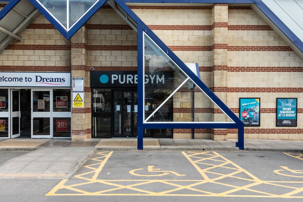 PureGym Chippenham: Gym exterior with entrance signage, parking spaces, and wheelchair accessibility markings.
