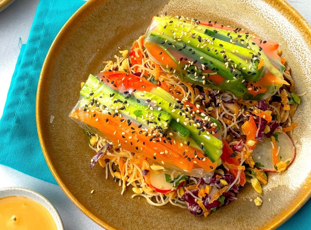 Two vegetable spring rolls with sesame seeds on a bed of salad in a brown bowl