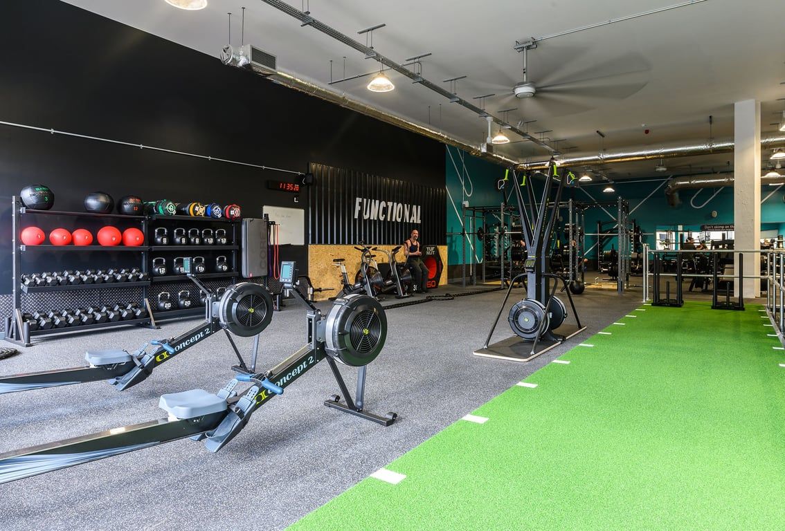 PureGym Bath Spring Wharf: Fitness studio with weight racks, kettlebells, medicine balls, turf area, and wall graphics.