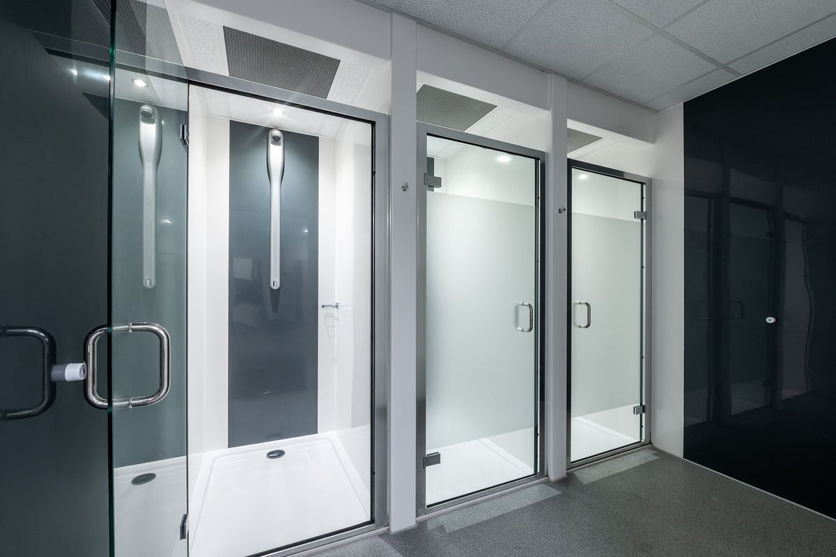 PureGym Weston-super-mare: Shower cubicles with glass doors and frosted panels in a changing room area.