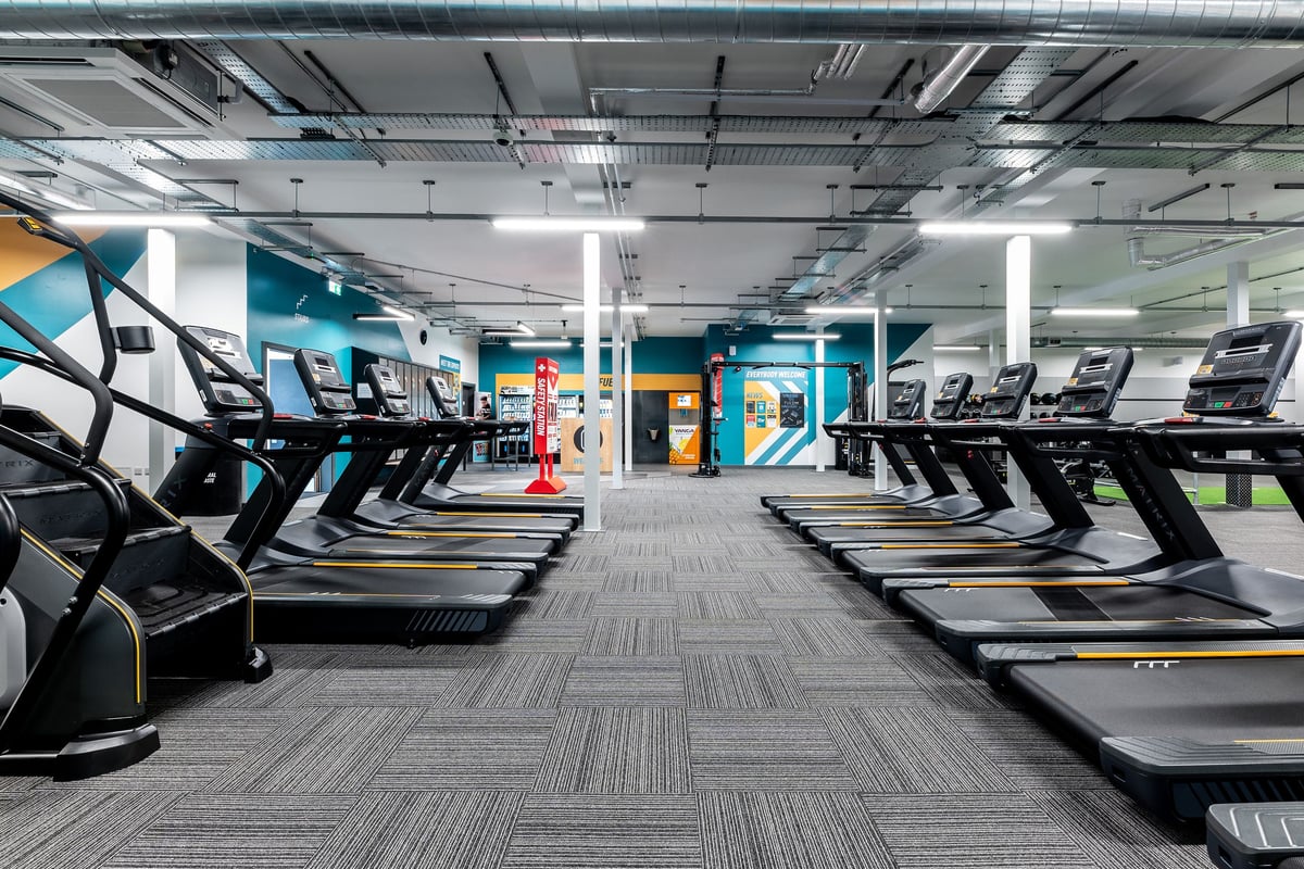 PureGym Shrewsbury Meole Brace: Rows of modern treadmills and cardio equipment in a bright, colorfully accented gym interior.