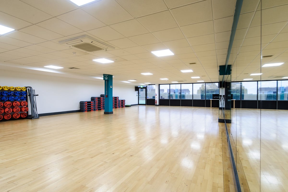 PureGym Bedford Heights: Wood flooring, mirrored walls, weight plates, exercise balls, sparse functional training area.