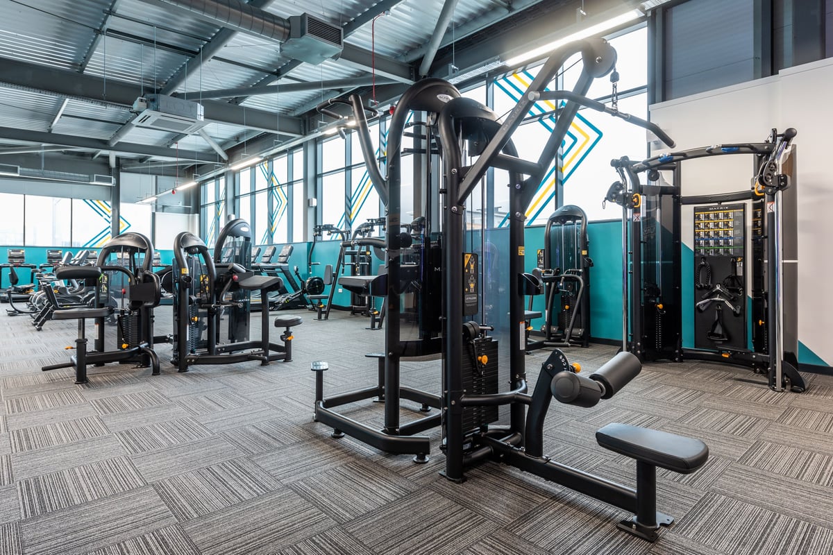 PureGym Plymouth Derriford: Fitness studio with weight machines, free weights, benches, and rubberized flooring.