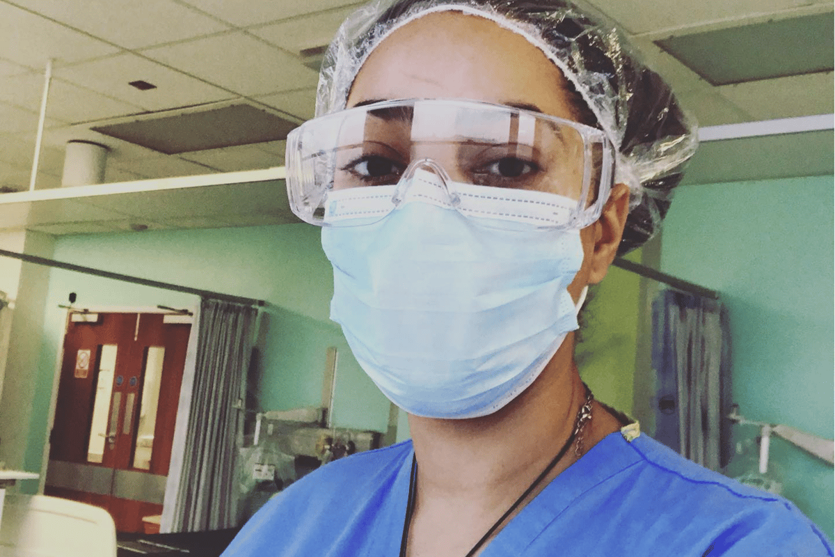 Healthcare worker wearing protective glasses, face mask, hairnet, and blue scrubs