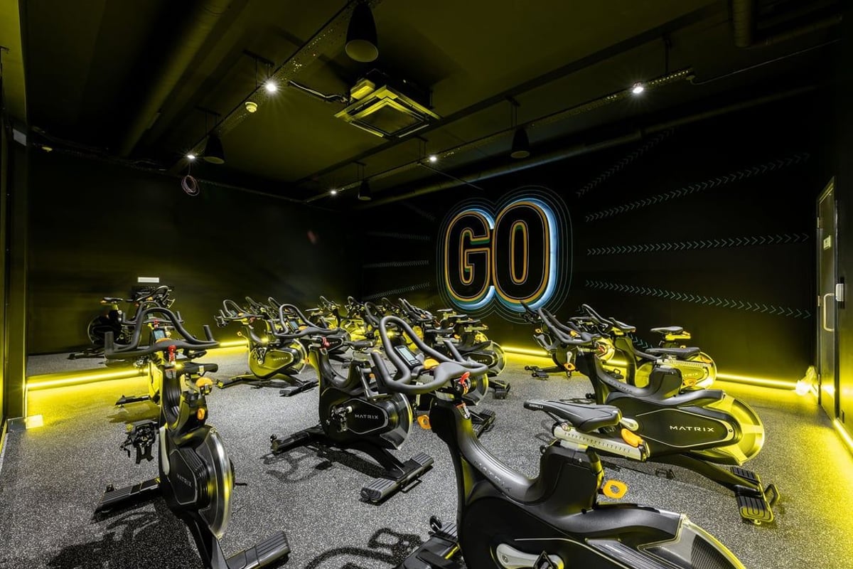 PureGym Sevenoaks: Rows of stationary exercise bikes with neon 'GO' signage in a dimly lit studio.