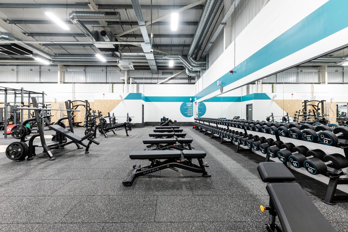 PureGym Great Yarmouth: Rows of squat racks, benches, free weights and weight plates in an industrial-style gym interior.