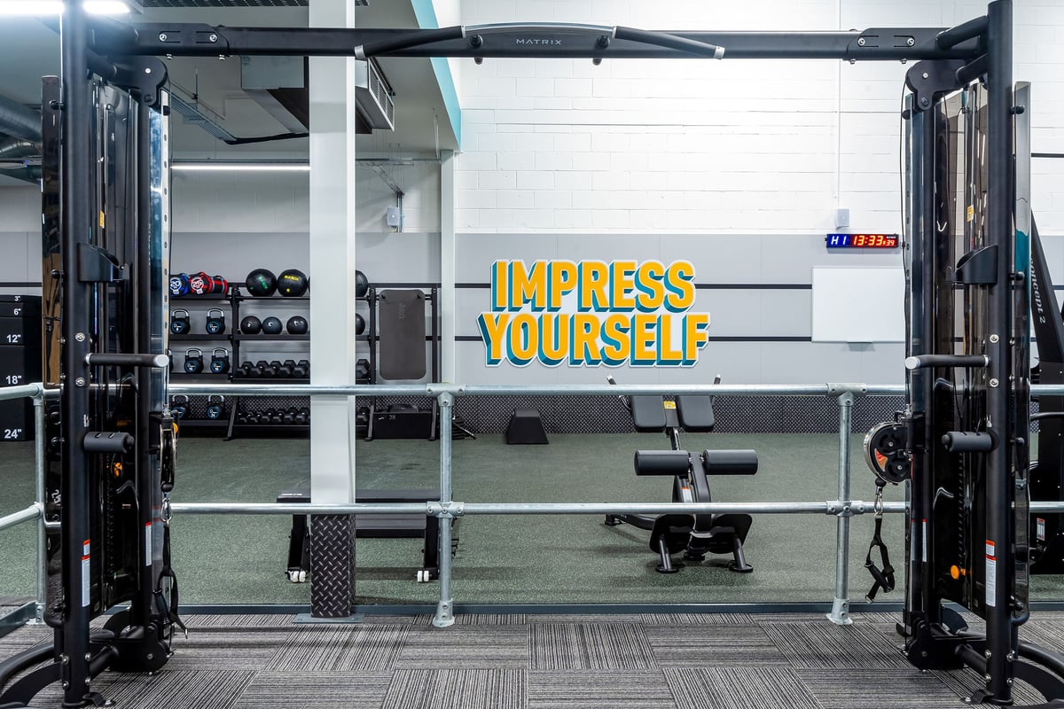 PureGym Linlithgow: Squat racks, weight benches, dumbbells, weight plates scattered around rubberized flooring.