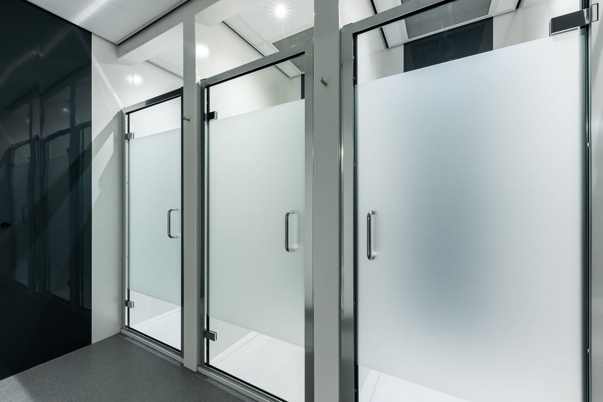 PureGym Great Yarmouth: Shower stalls with glass doors and handles in a tiled bathroom area.
