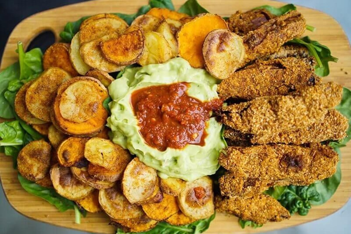 Süßkartoffelchips, Guacamole mit Salsa und paniertes Hähnchen auf Spinatblättern