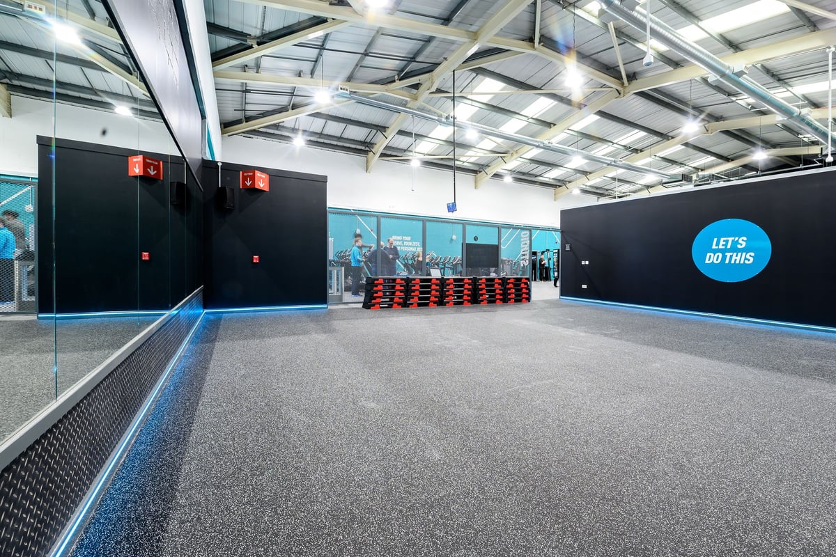PureGym Burgess Hill: Gym studio with treadmills, weight racks, rubberized flooring, and motivational wall signage.