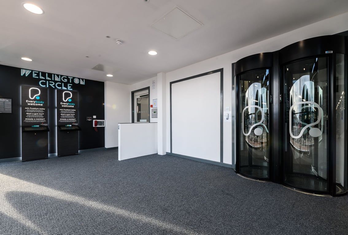 PureGym Aberdeen Wellington Circle: Lift entrance area with weightlifting plates artwork on glass doors.