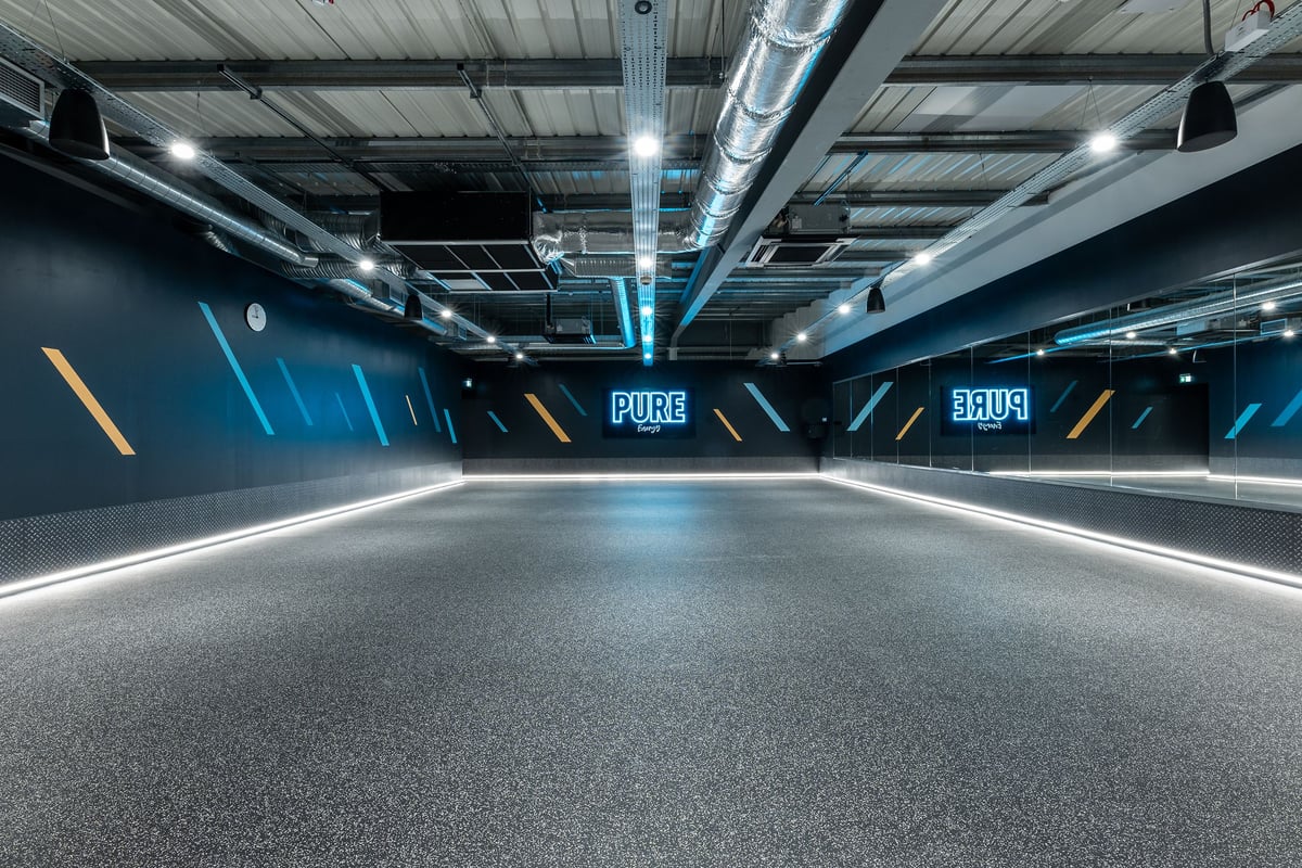 PureGym Watford Waterfields Retail Park: Treadmills along teal and black walls with neon lighting in an indoor running track.