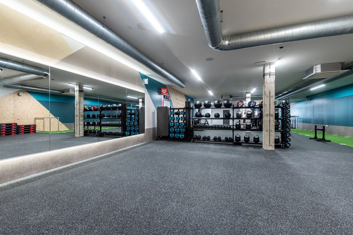 PureGym London Welling: Weight racks, barbells, dumbbells, rubberised flooring in a basement gym setup.