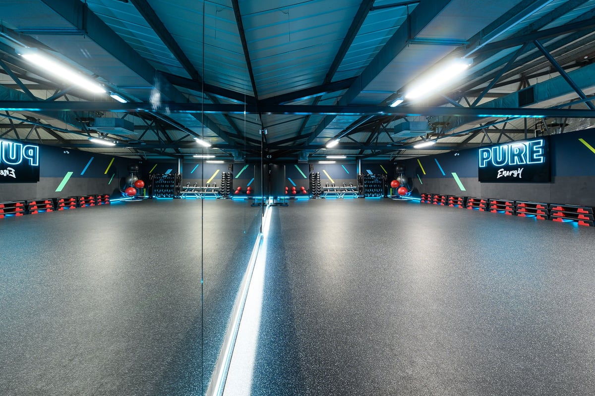 PureGym Reading Caversham Road: Indoor race track with blue lighting, wall graphics, and tire barriers.