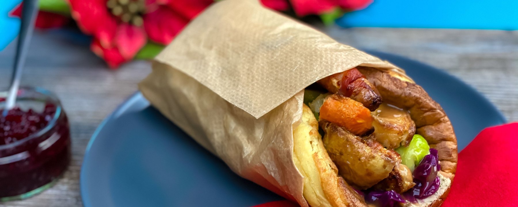Christmas Yorkshire pudding wrap filled with roast potatoes and vegetables on a blue plate