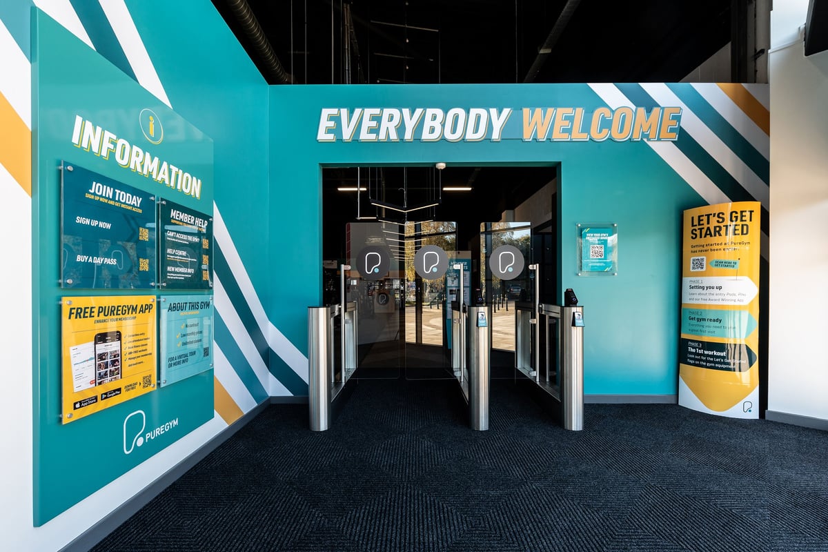 PureGym Stockton-on-tees Teesside Park: Entrance area with information signage, turnstiles, and carpet flooring.