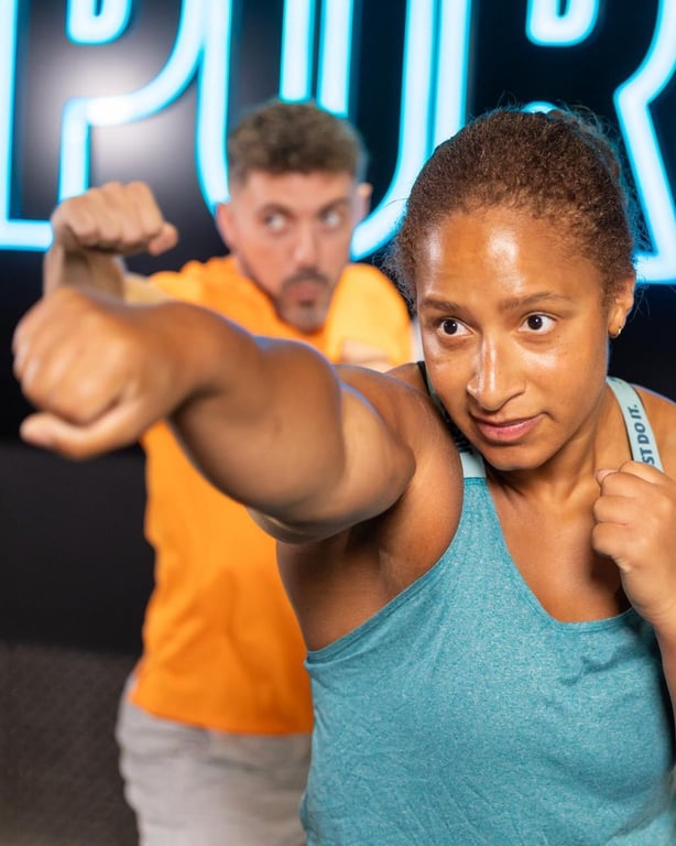 Konzentrierte Athleten trainieren mit Kettlebells unter Neonlichtern in einer energiegeladenen PureGym-Umgebung
