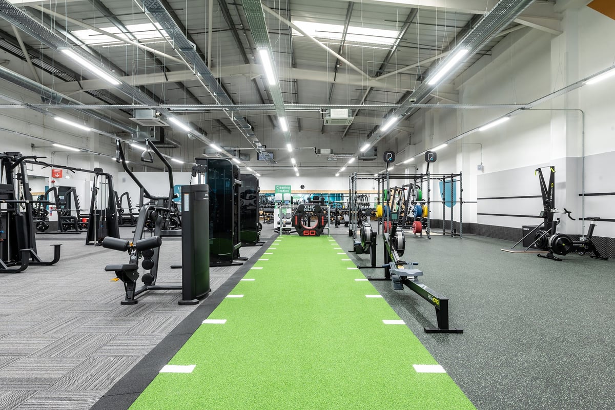 PureGym Ashford Warren Retail Park: Weight machines, resistance equipment, green turf area, and ceiling-mounted lighting.