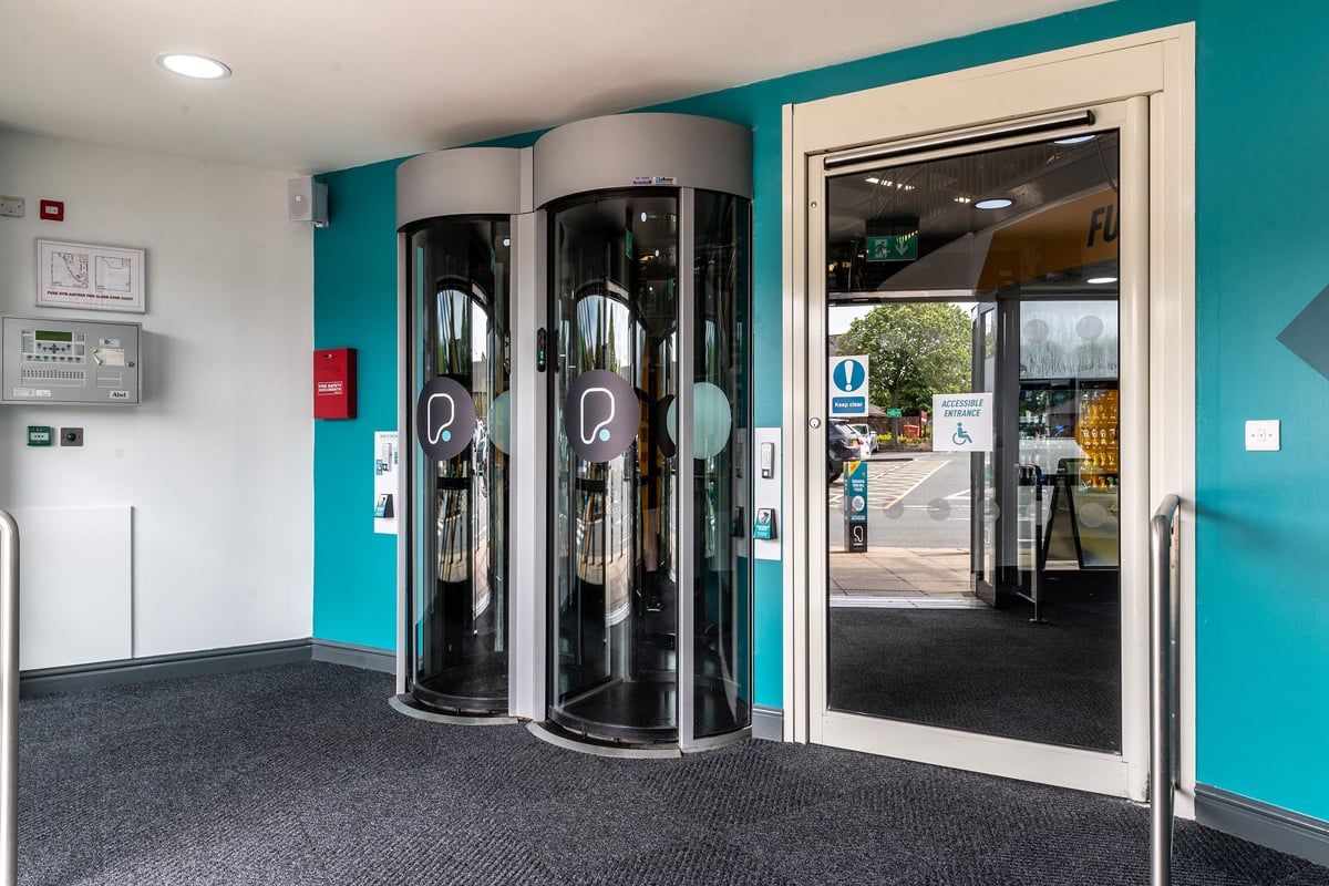 PureGym Aintree: Two revolving doors, access turnstiles, and an exterior door.